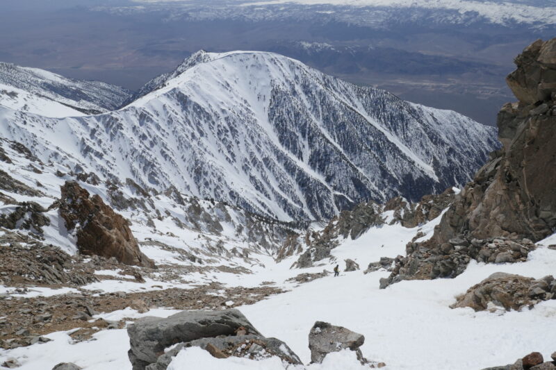 Looking down the main line from near the top. Coverage is a little thin up top but good considering the exposure to the wind. We had to walk down a short distance to get to the snow. On east aspects you could have dropped directly from the summit. In the background is the N face of Benton peak. The cornices are visible and you can see the winter-y snow that is still there and could slide.